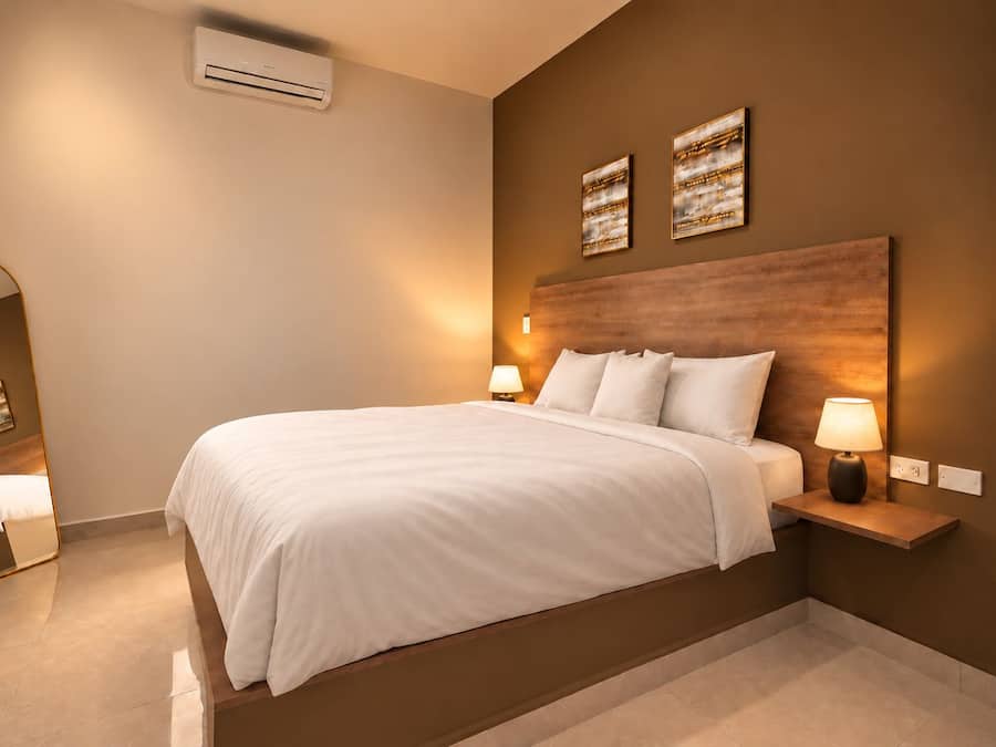 A modern hotel room with a large bed, bedside tables with lamps, and artwork on the walls.
