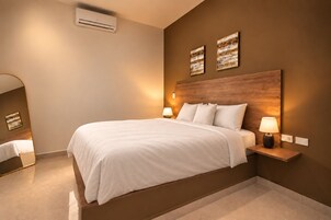 Una habitación de hotel moderna con una cama grande, mesitas de noche con lámparas y obras de arte en las paredes.