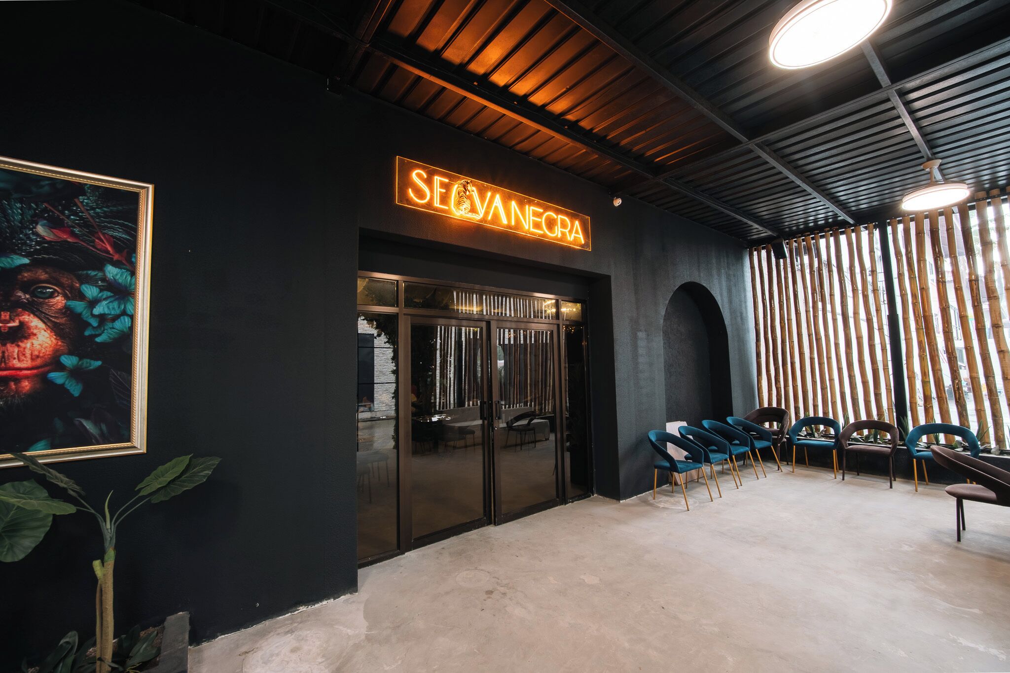 A modern interior with a neon sign reading 'SEVANECRA,' a glass door entrance, and a row of chairs.