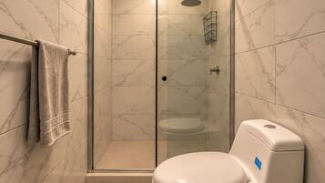 A modern bathroom with a glass-enclosed shower, a toilet, and a towel rack.