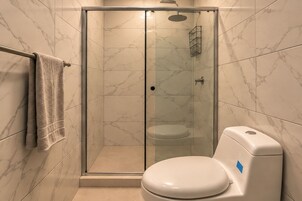 A modern bathroom with a glass-enclosed shower, a toilet, and a towel rack.