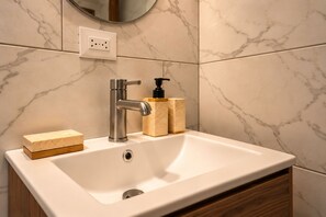 A bathroom with a white sink, a modern faucet, a mirror, and marble-patterned walls. - La Palma Experience (Panama City)