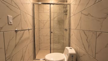 Un baño con cabina de ducha, inodoro y paredes de mármol.