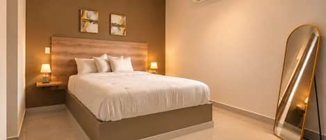 A modern bedroom with a large bed, bedside lamps, an air conditioning unit, and a full-length mirror.