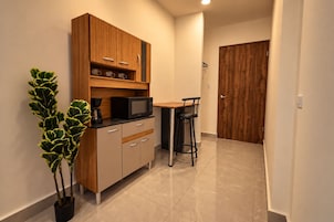 Una cocina compacta equipada con microondas, cafetera y un pequeño comedor con dos sillas.