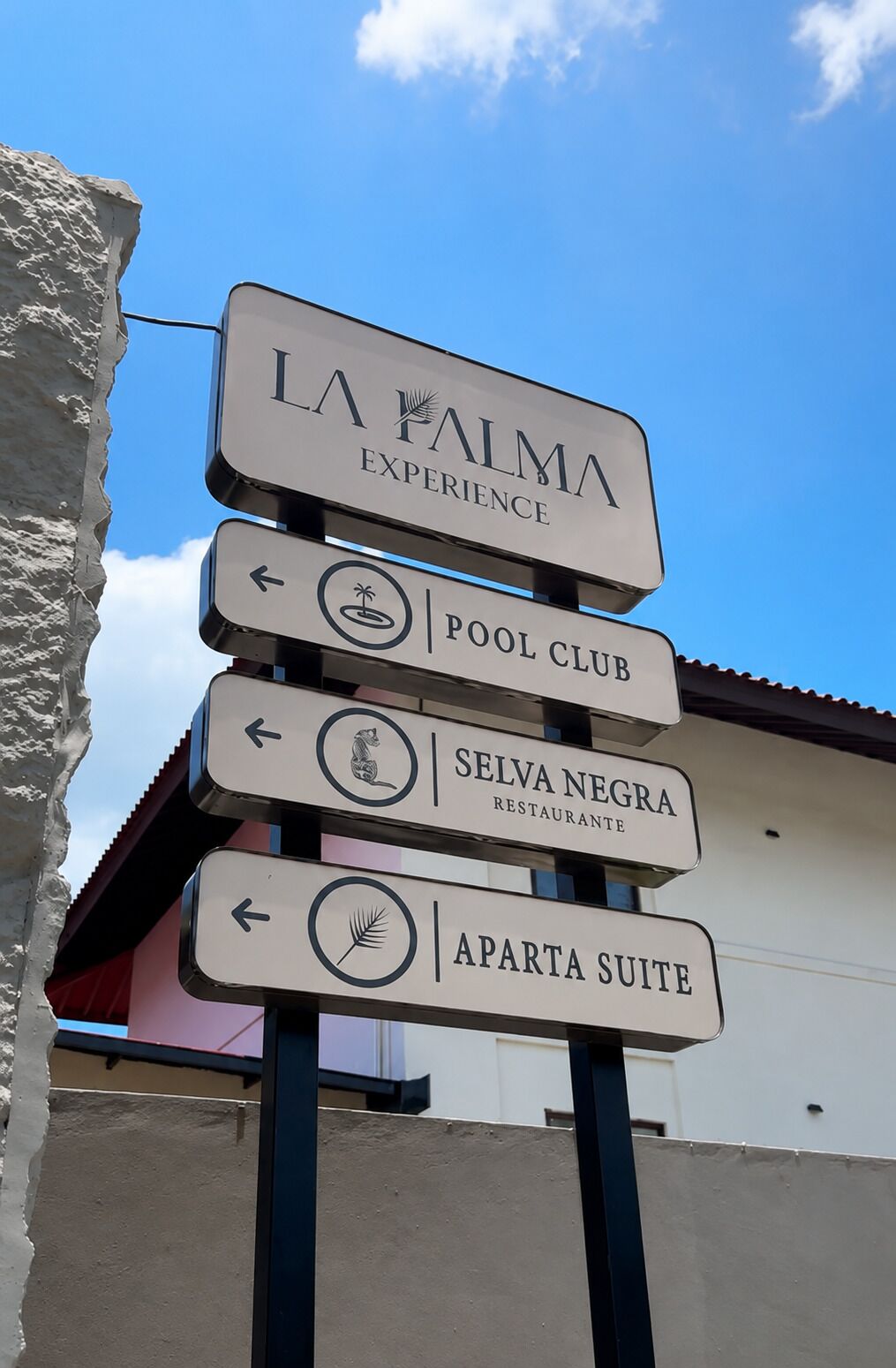 A directional sign with multiple arrows pointing to different amenities including a pool club, restaurant, and apartments.
