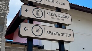 A directional sign with multiple arrows pointing to different amenities including a pool club, restaurant, and apartments. - La Palma Experience (Panama City)