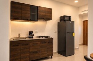 Una cocina moderna con armarios de madera, estufa a gas, cafetera y refrigerador negro.