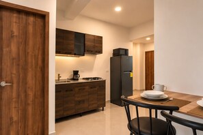 Una cocina compacta con armarios de madera, un refrigerador negro, un microondas y una cafetera.