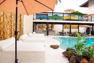 Uma área à beira da piscina com sofás brancos, piscina e mobiliário de exterior.