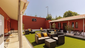 Eine Terrassenanlage im Freien mit künstlichem Rasen, Korbmöbeln und einem Basketballkorb.