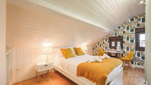 Ein Schlafzimmer mit Bett, Nachttisch, Lampe und einem kleinen Tisch mit Stühlen.