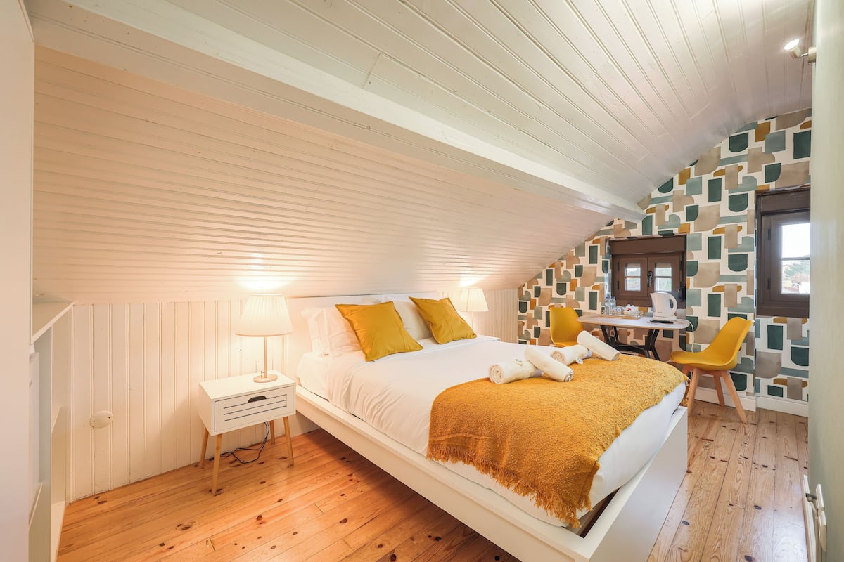 Una camera da letto con un letto, un comodino, una lampada e un tavolino con sedie.