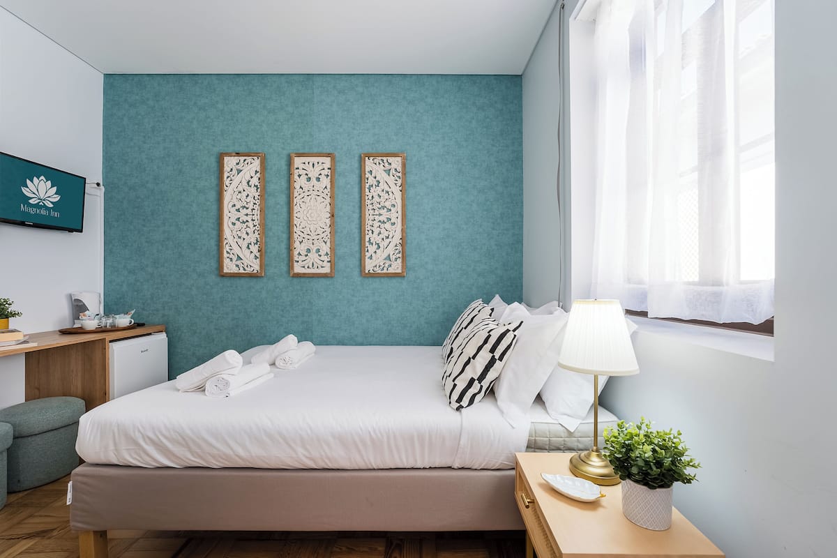 Una camera d'albergo con un letto, comodino, lampada e pannelli decorativi a parete.