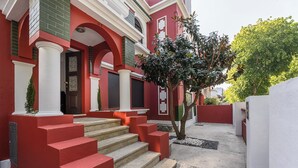 Ein Gebäude mit roten und weißen Außenwänden, einer Treppe aus Stein, die zu einer Tür führt, und einem kleinen Baum im Vordergrund.