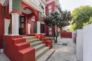 A building with red and white exterior walls, a set of stone steps leading to a door, and a small tree in the foreground. - Magnolia Inn (Aveiro)