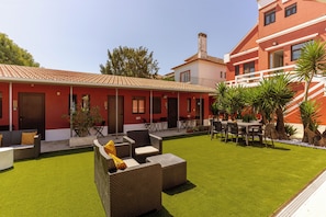 A red building with a tiled roof, outdoor seating, and a well-maintained lawn. - Magnolia Inn (Aveiro)