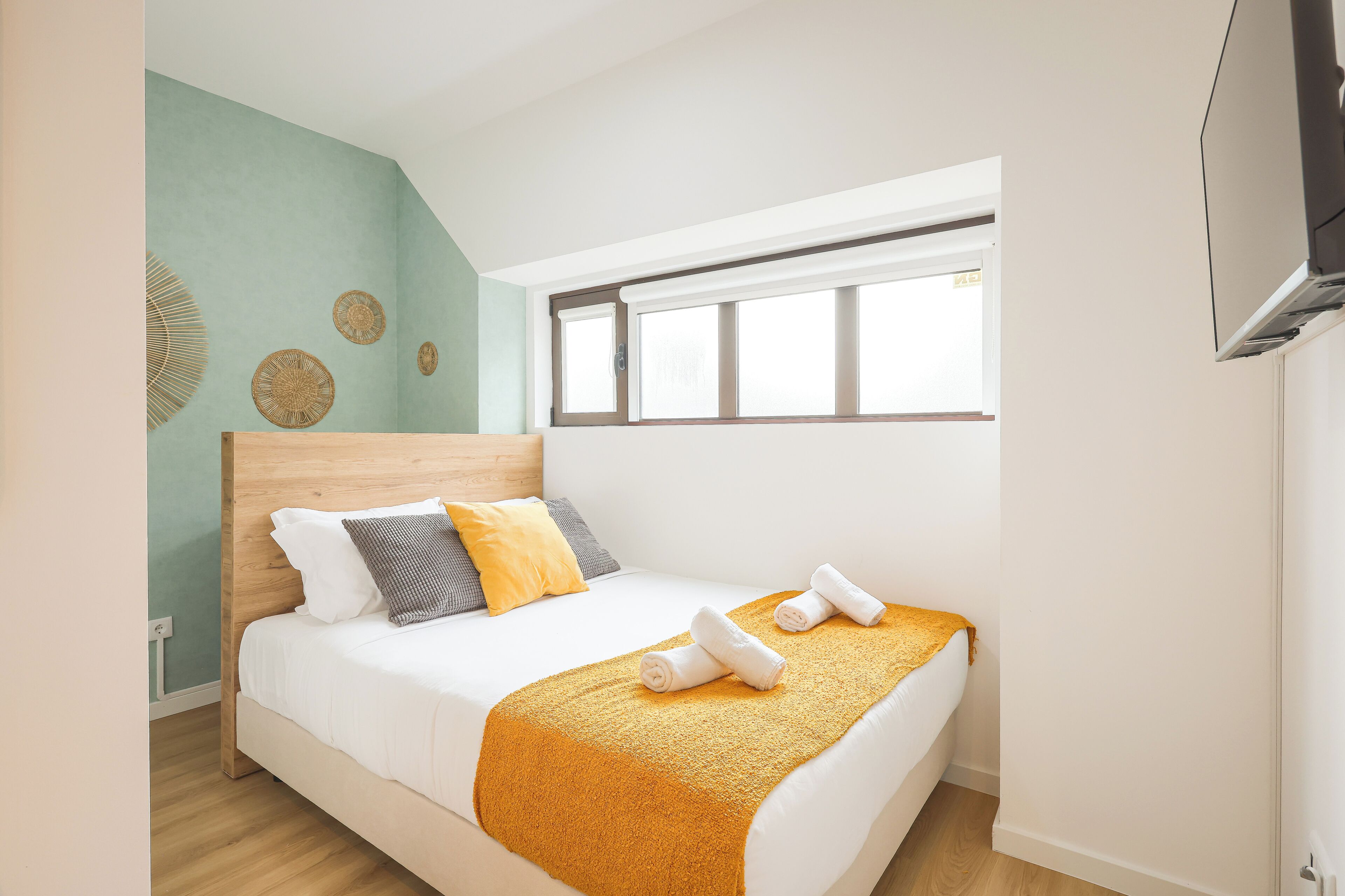 A bedroom with a bed, a window, and a wall-mounted air conditioner.