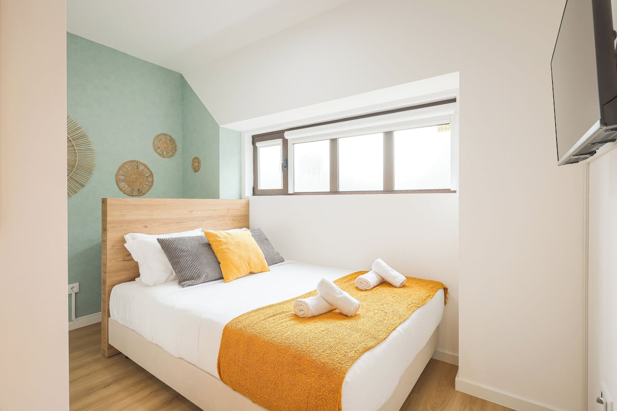 Una camera da letto con un letto, una finestra e un condizionatore d'aria a parete.
