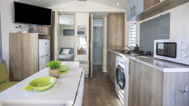 Une cuisine compacte équipée d’un four à micro-ondes, d’une cuisinière et d’un lave-linge.