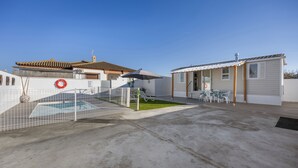 Il s’agit d’une propriété résidentielle dotée d’une piscine, d’un espace clôturé et d’une terrasse aménagée avec du mobilier d’extérieur.