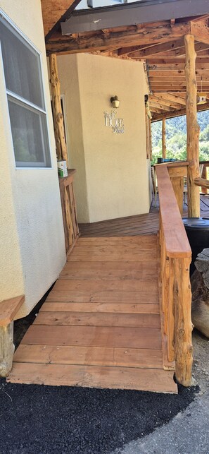 A wooden deck leading to a building with a 'Welcome Home' sign, a window, and a wooden railing.