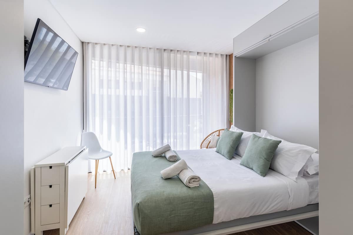 A modern bedroom with a bed, a desk, and a chair.