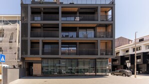 Un immeuble à plusieurs étages doté de balcons, de grandes fenêtres et d’un panneau indiquant un passage piéton.