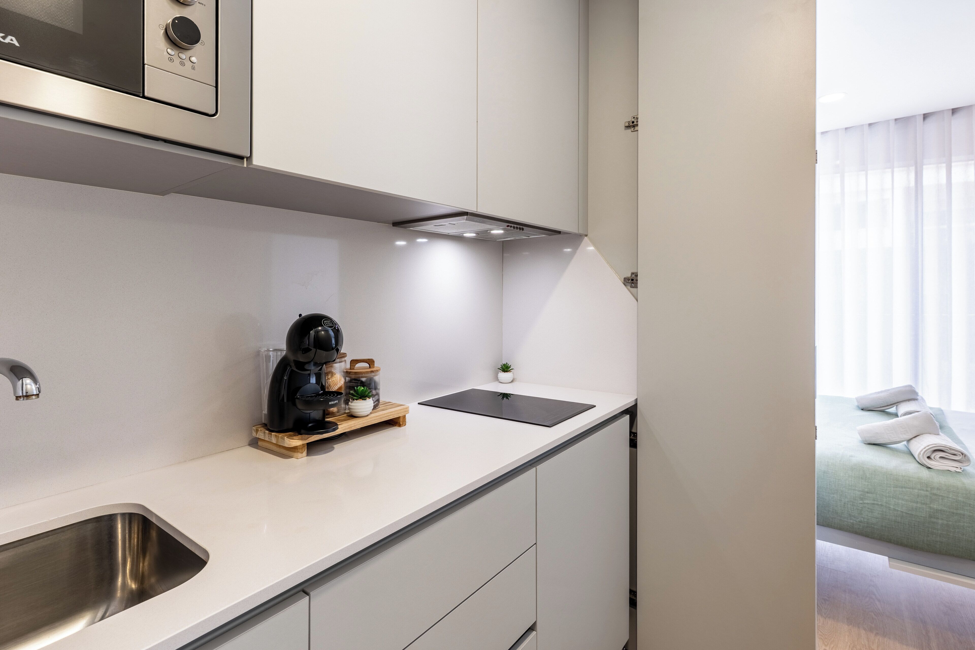 A modern kitchen with a built-in microwave, a coffee machine, and a small potted plant.