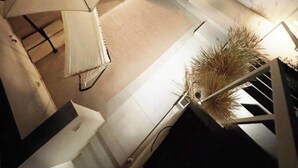 Overzicht vanuit de hoogte van een kamer met een bed, een bureau, een stoel, een klein tafeltje en een plant in een pot.