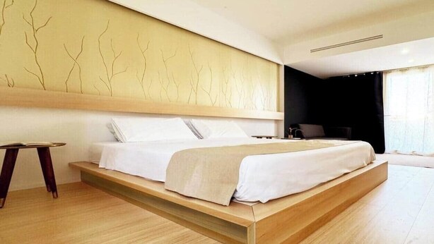 Een moderne slaapkamer met een bed, een nachtkastje en een muur met een ontwerp geïnspireerd door een boom.