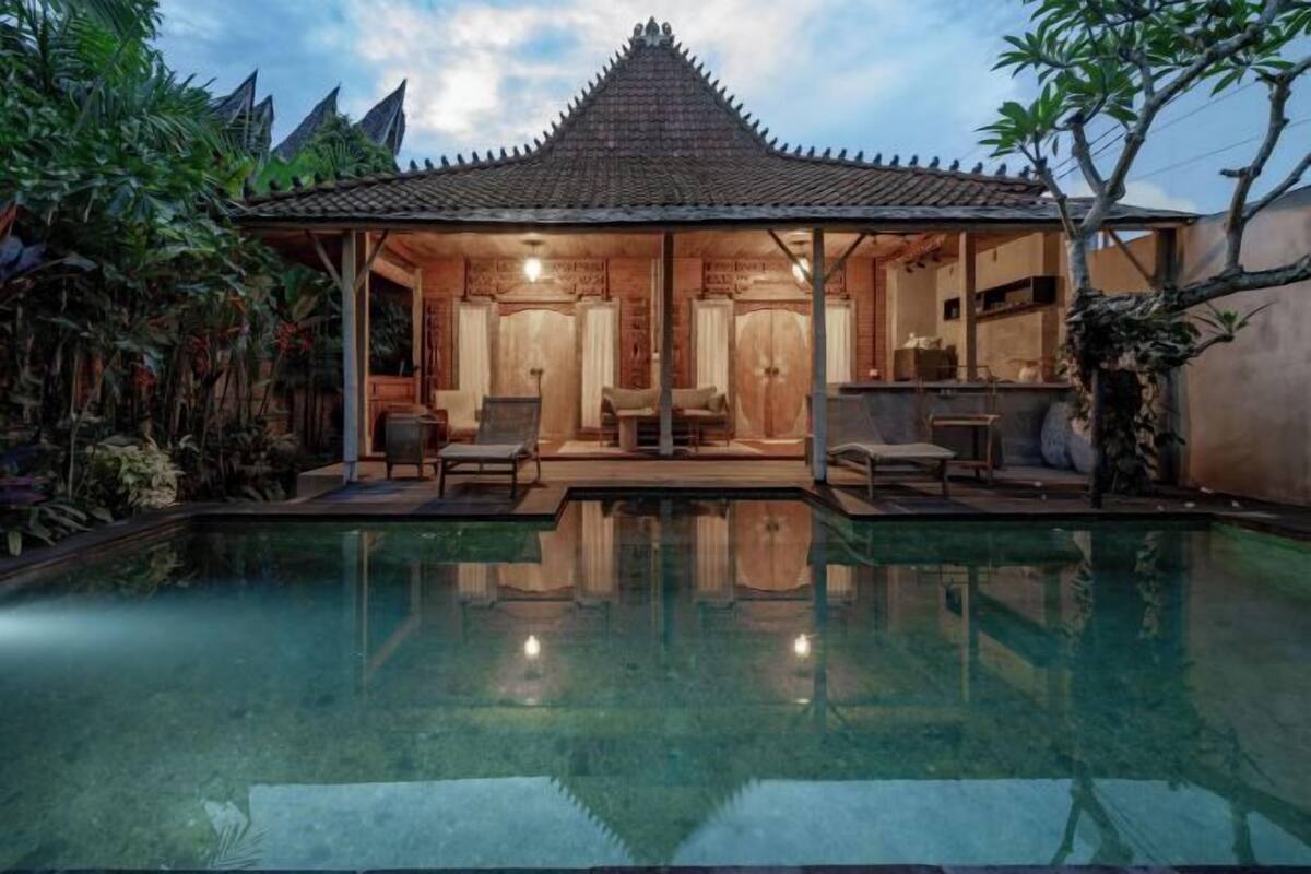 A traditional-style building with a tiled roof, a pool in front, and wooden furniture inside.