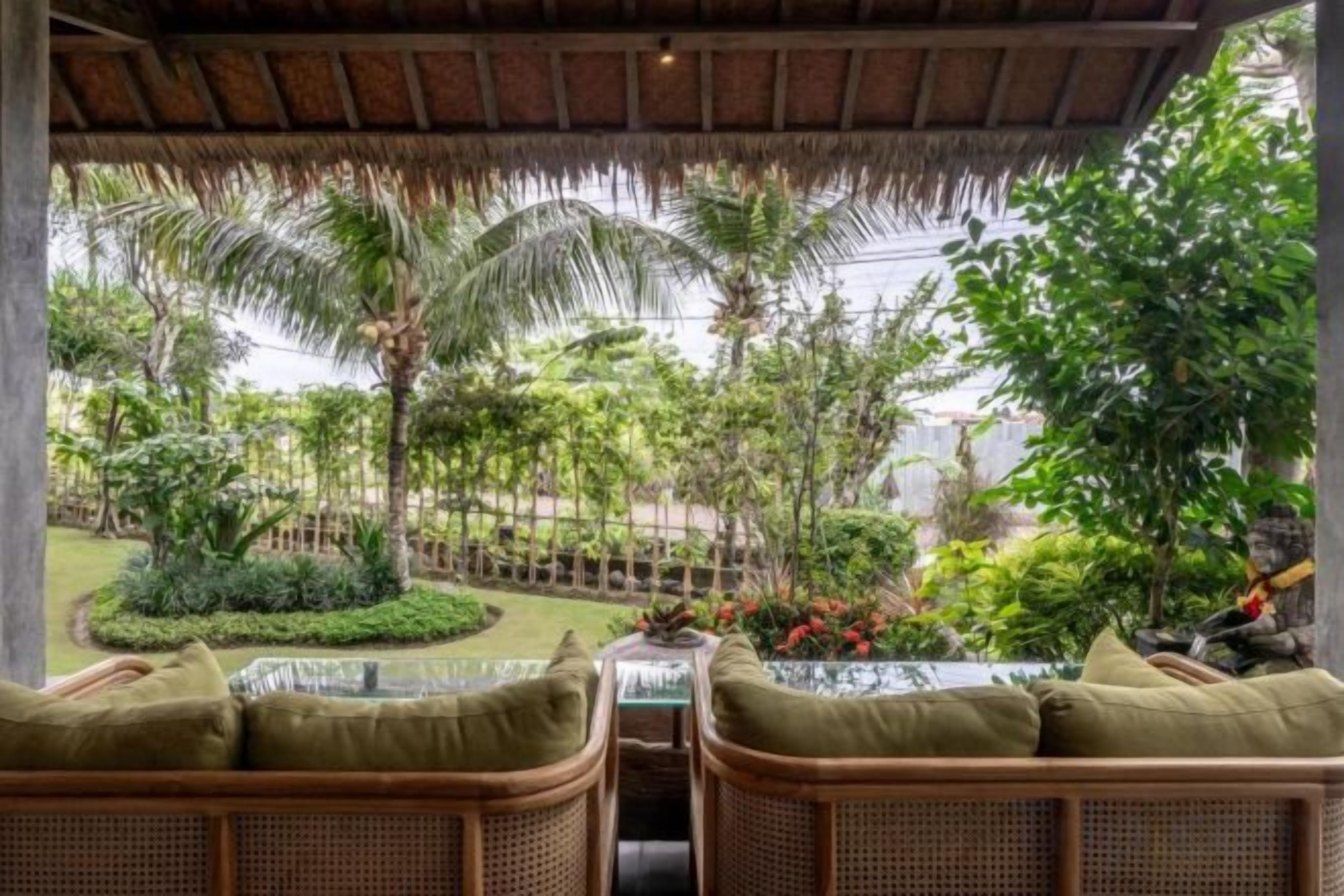 Un espace extérieur aménagé avec des meubles en osier et offrant une vue sur un jardin paysager.