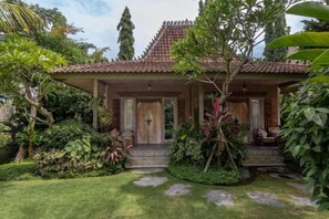 A traditional house with a tiled roof, surrounded by lush greenery and a well-maintained lawn. - Premadhan Sanctuary (Bali)