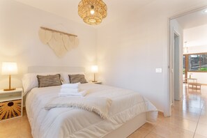 Et soveværelse med en stor seng, sengeborde med lamper, en dekoration på væggen og udsigt udad.