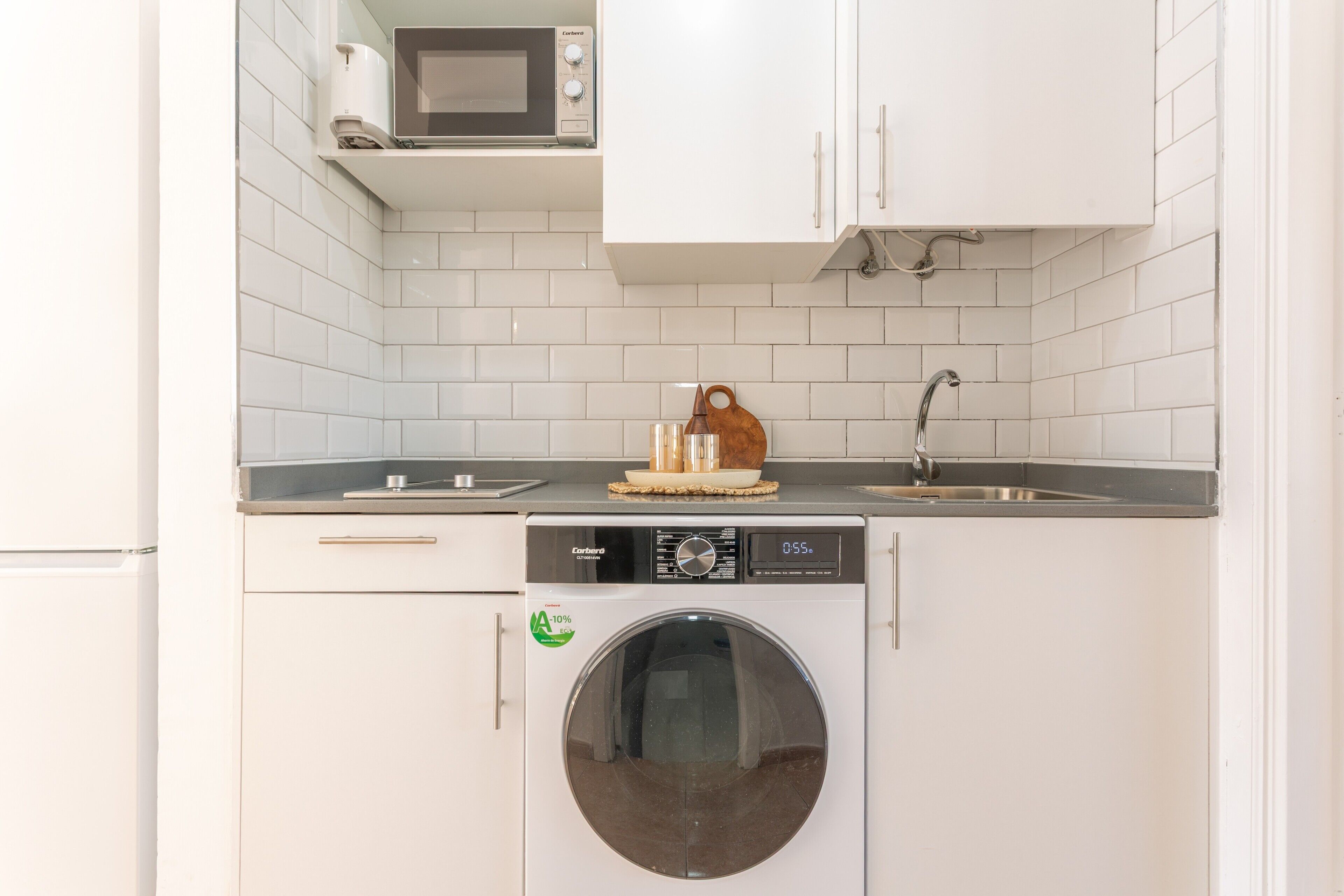 A compact kitchen with a washing machine, a microwave, and a sink.