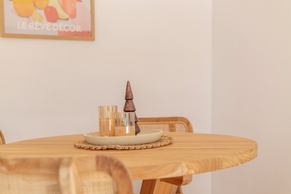 A round wooden table with a woven placemat, a candle holder, and two glass candle holders.