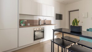Una cucina moderna con mobili bianchi, forno a incasso, piano di lavoro nero e un tavolo con panche.