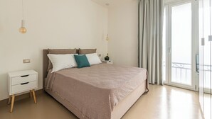 Una camera da letto moderna con un ampio letto, un comodino e vista all'esterno tramite una porta scorrevole in vetro.
