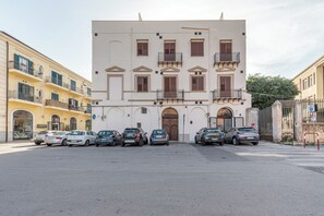 A building with a central entrance, multiple balconies, and parked cars in front. - Crispi Suite in Palermo by Wonderful Italy (Palermo)