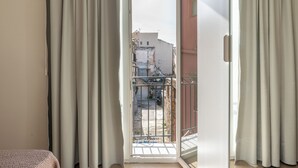 Una stanza con una porta scorrevole in vetro che dà su un balcone con ringhiera in metallo.