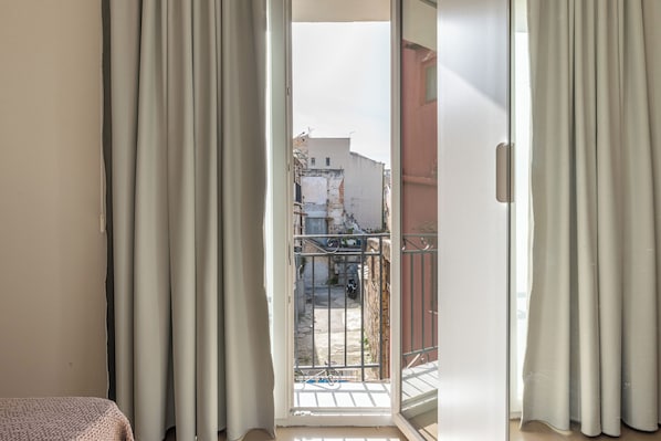 A room with a sliding glass door leading to a balcony with a metal railing.