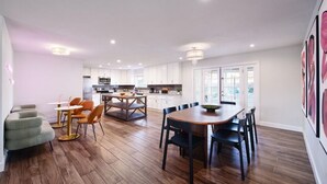 A spacious kitchen with white cabinets, a dining area with a wooden table and chairs, and a modern chandelier. - Old Town Scottsdale Retreat: 5BD, 2BA with a Pool, BBQ Grill, & More (Scottsdale)