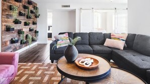 A modern living room with a sectional sofa, a round coffee table, and a vertical garden wall. - Old Town Scottsdale Retreat: 5BD, 2BA with a Pool, BBQ Grill, & More (Scottsdale)