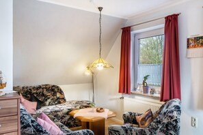 Una camera accogliente con un letto, una scrivania, una sedia, una lampada e una finestra con tende.