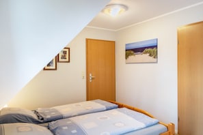 Una camera da letto con un letto, una porta in legno e un quadro appeso al muro.