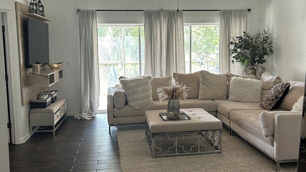 A spacious living room with a large sofa, a coffee table, and a ceiling fan. - Beautiful  2-bedroom/2-bath condo with AC close to beach & shopping in  Naples (Naples)