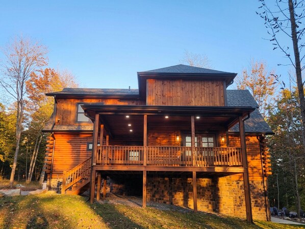 Une cabane en bois dotée d’un balcon, avec des fondations en pierre et un ciel dégagé.