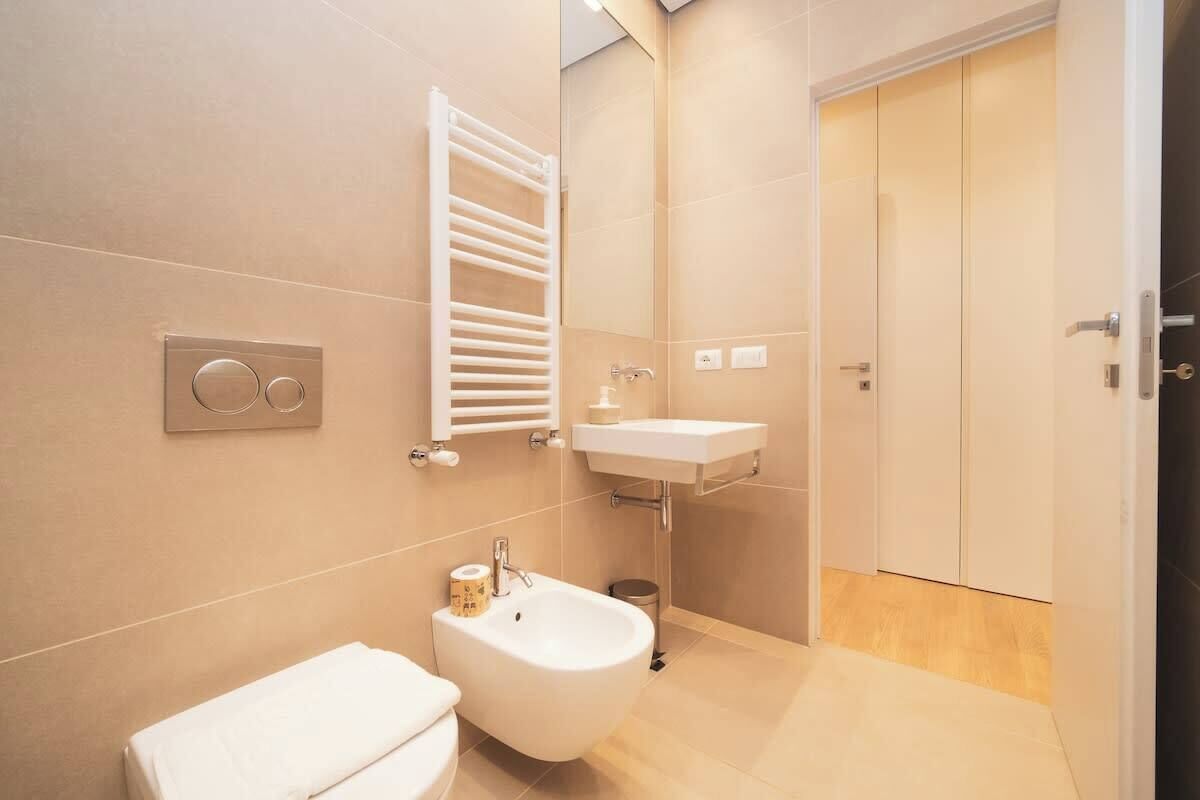 Un baño moderno con inodoro, bidé, lavamanos, toallero y una puerta.