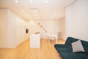 A modern living space with a kitchen, dining area, and a green sofa.